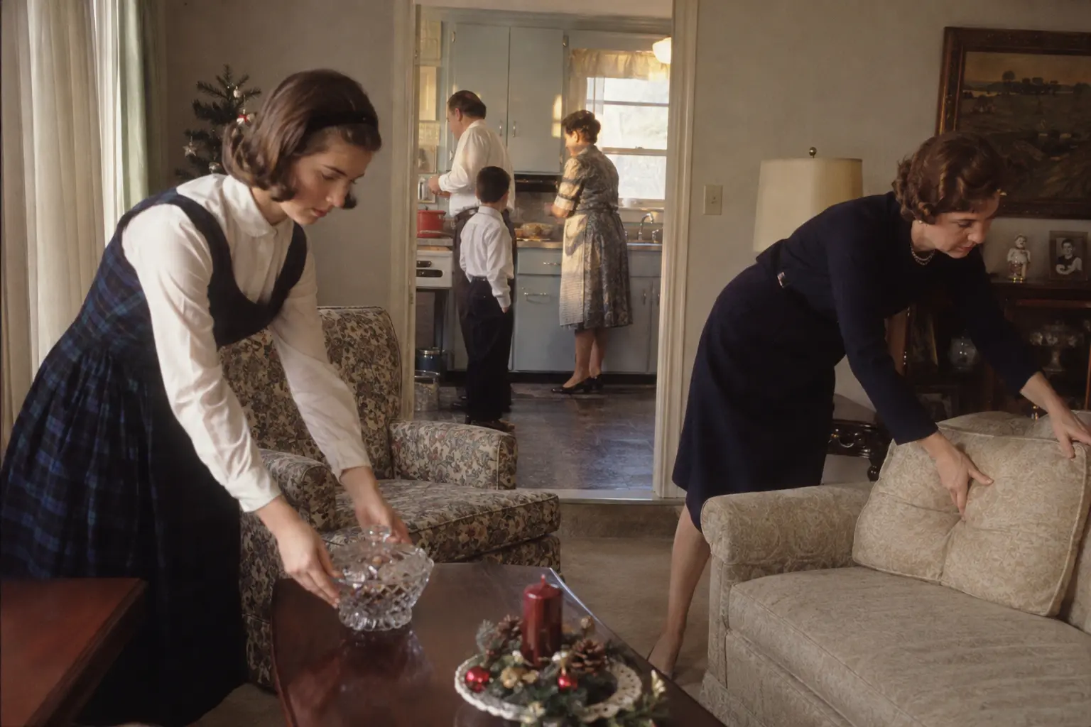A parent straightening cushions in a formal mid-century living room